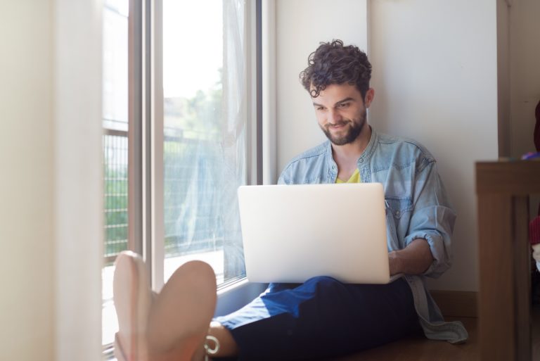 man working on a laptop in a bay window