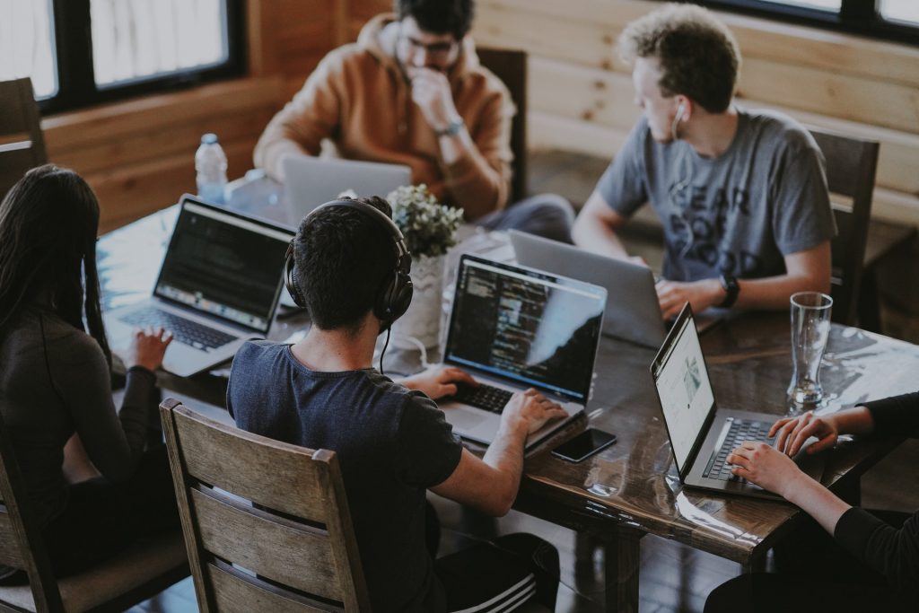 multiple people working on laptops and working together at a table