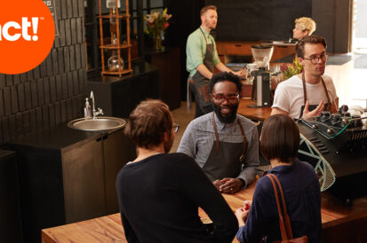 A groupe of people ina dim cafe with an act logo on the top left