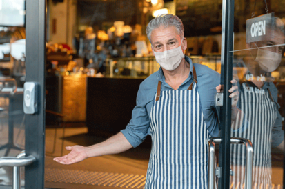 man in medical mask holding door open